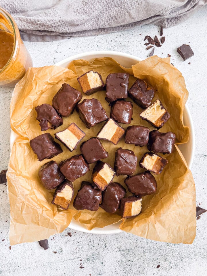 raw gluten free and vegan twix bites in large plate with some cut showing layers