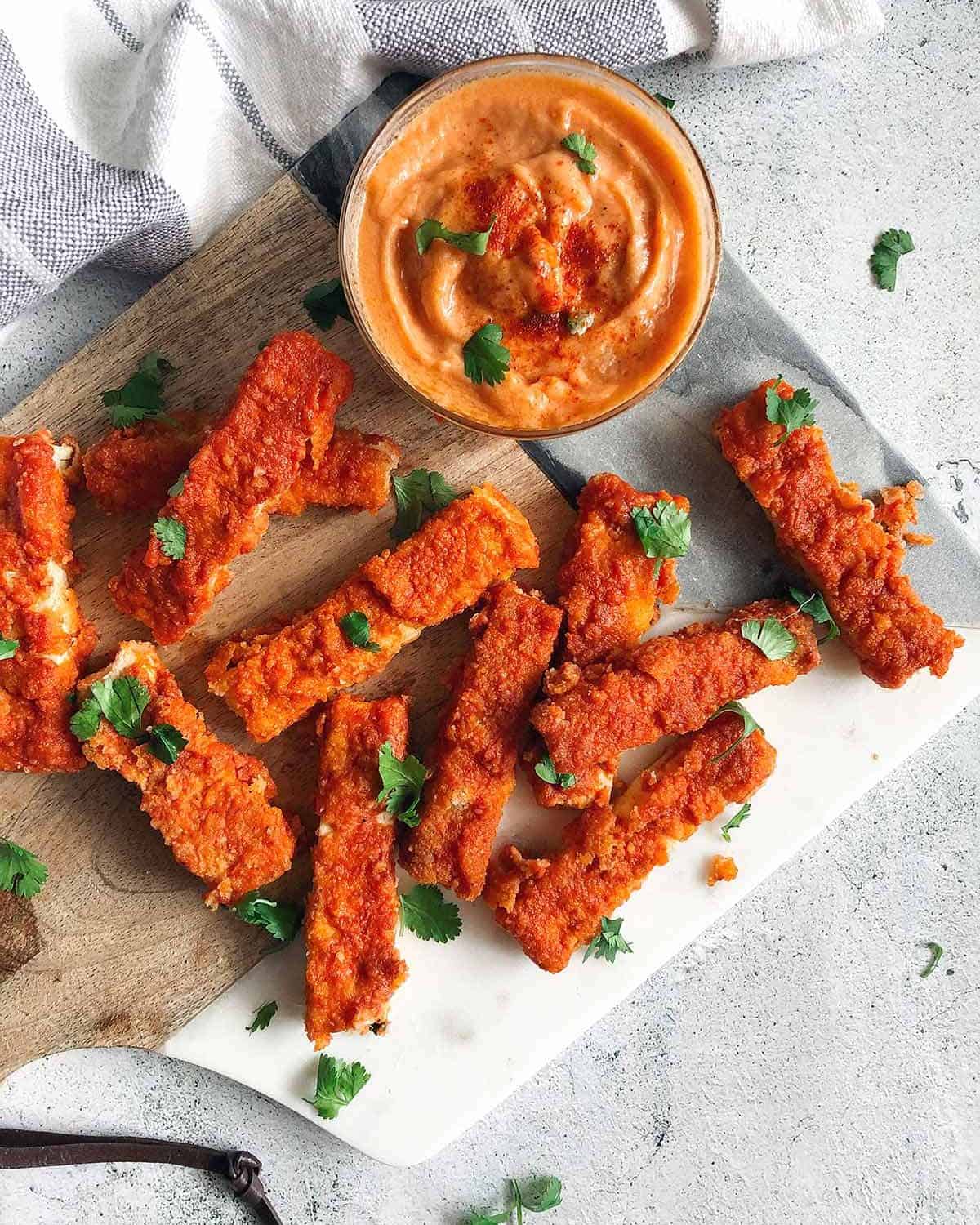 spicy tofu buffalo wings on a marble wooden cutting board with spicy buffalo mayo dipping sauce on the side