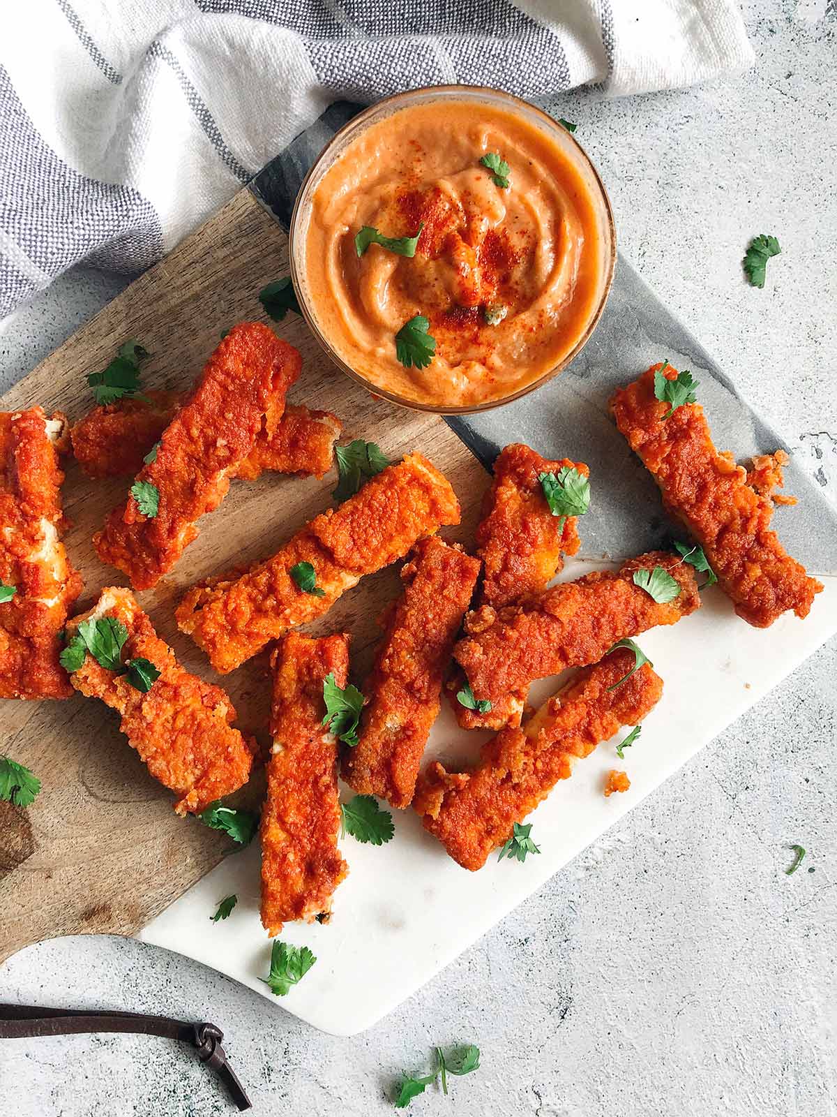 spicy tofu buffalo wings on a marble wooden cutting board with spicy buffalo mayo dipping sauce on the side