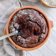 sweet potato brownies in ramekin with silver spoon dug in to the center with powdered sugar bowl in the corner