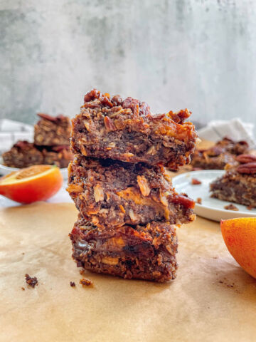 3 Vegan Peach Crumble Bars with Candied Pecans stacked with other bars blurred in the background