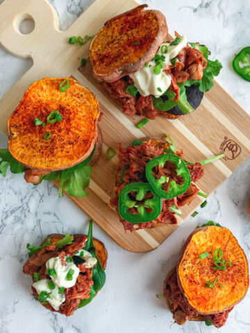 sweet potato vegan jackfruit pulled pork bbq sliders on cutting board with greens and avocado mayo