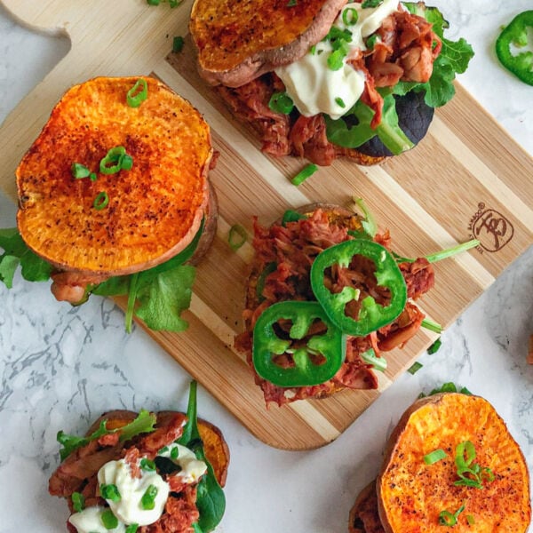 sweet potato vegan jackfruit pulled pork bbq sliders on cutting board with greens and avocado mayo