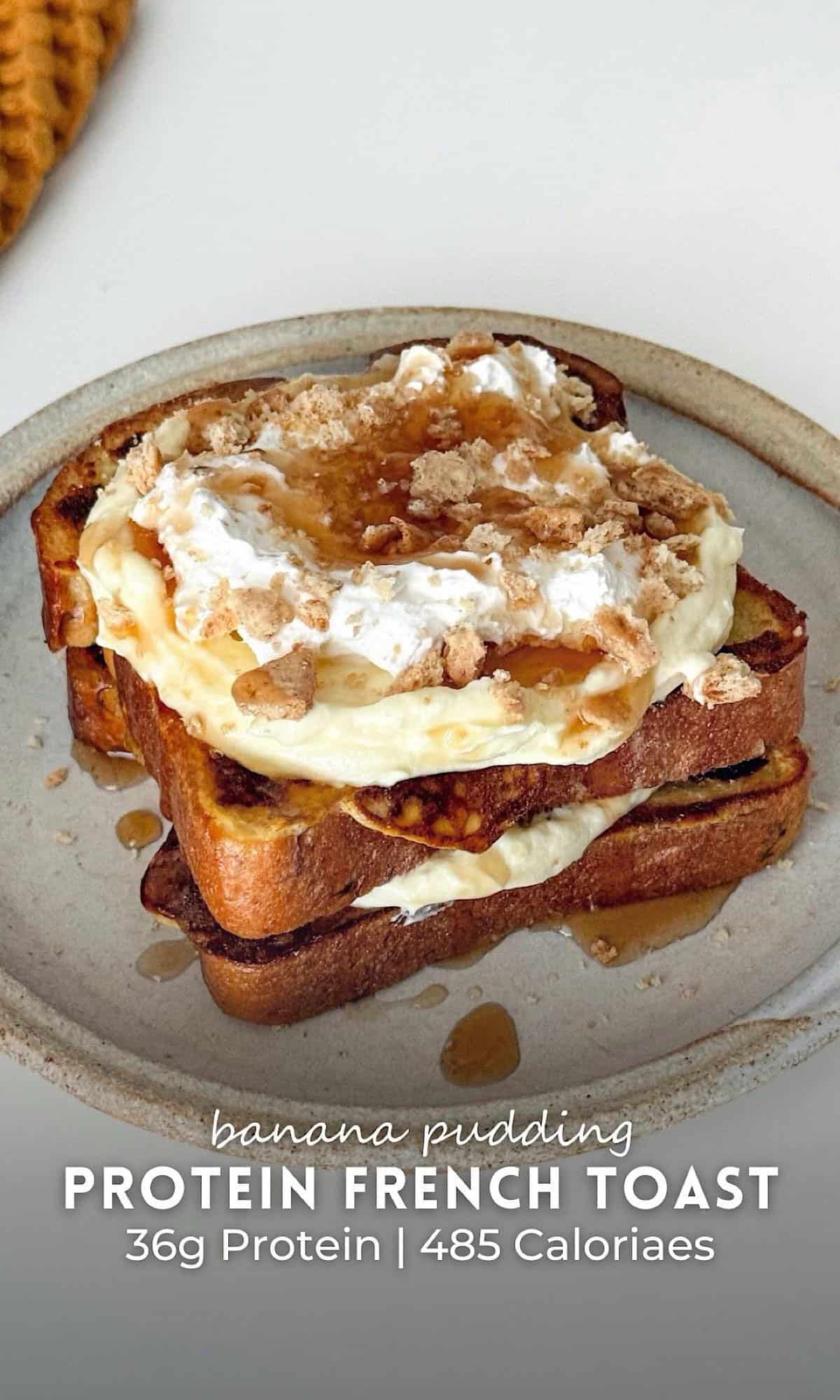 Banana Pudding Protein French Toast 9 Banana pudding protein French toast stacked high with creamy filling, whipped topping, crushed cookies, and a drizzle of syrup on a rustic ceramic plate.