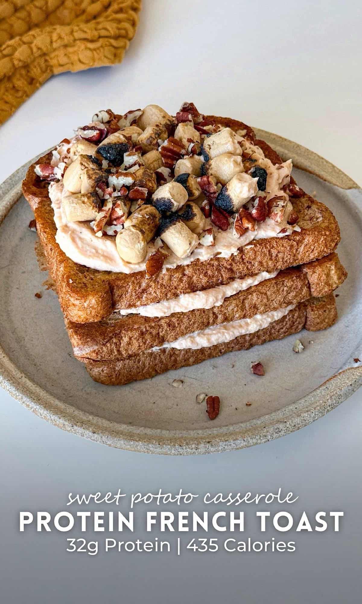Sweet Potato Casserole French Toast 10 A cozy stack of sweet potato casserole French toast layered with whipped filling and topped with toasted mini marshmallows and chopped pecans, served on a ceramic plate with a soft orange kitchen towel in the background.