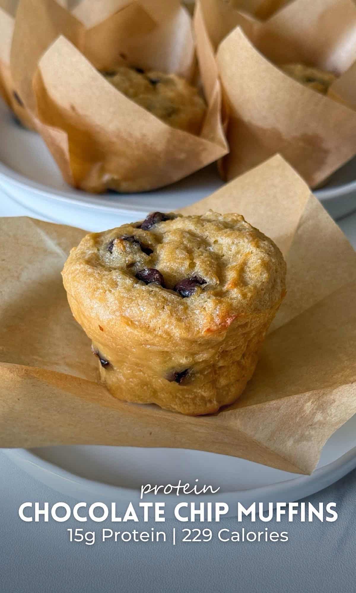 Freshly baked protein chocolate chip muffins in parchment paper liners on white plates, with melted chocolate chips throughout and a soft golden brown texture.