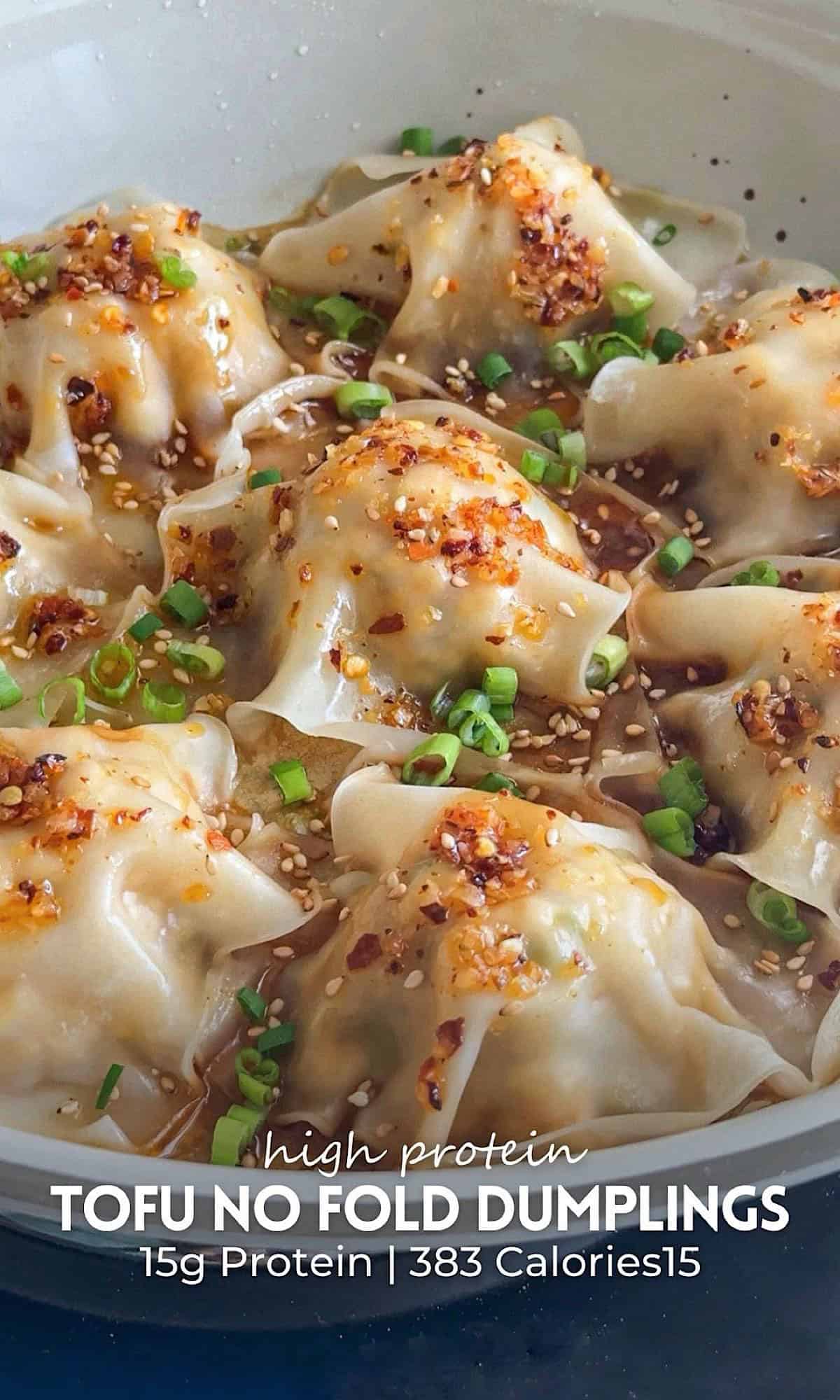 Tofu no fold dumplings arranged in a white nonstick pan, topped with chili crisp, sesame seeds, and chopped green onions.