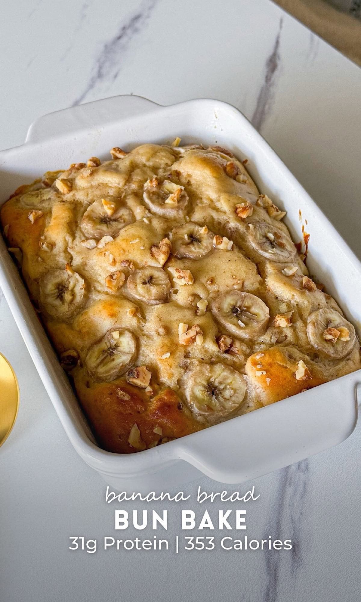 Banana bread bun bake topped with sliced bananas and chopped walnuts in a white baking dish.