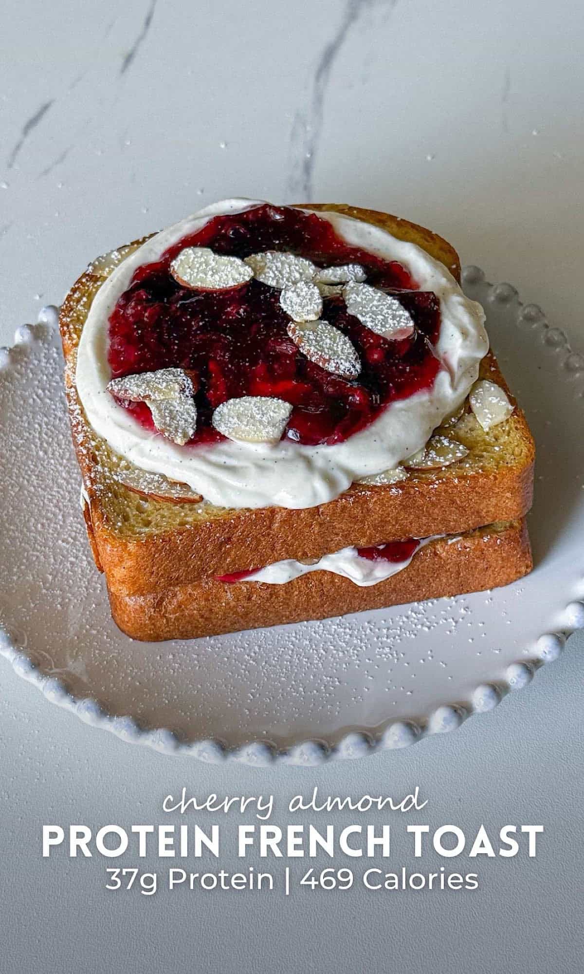 Cherry Almond Protein French Toast 10 Cherry almond protein French toast layered with vanilla Greek yogurt and homemade cherry filling, topped with sliced almonds and powdered sugar, served on a white beaded plate.