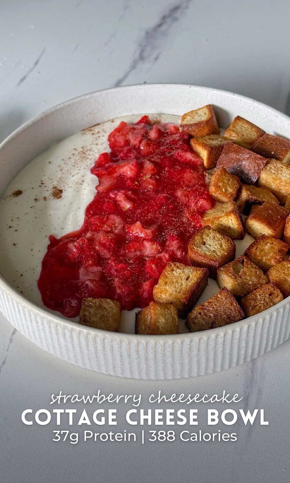 Strawberry Cheesecake Cottage Cheese Bowl with Cinnamon Toast Crunch 10 Strawberry cheesecake cottage cheese bowl topped with warm strawberry compote and crispy cinnamon toast cubes in a white bowl.
