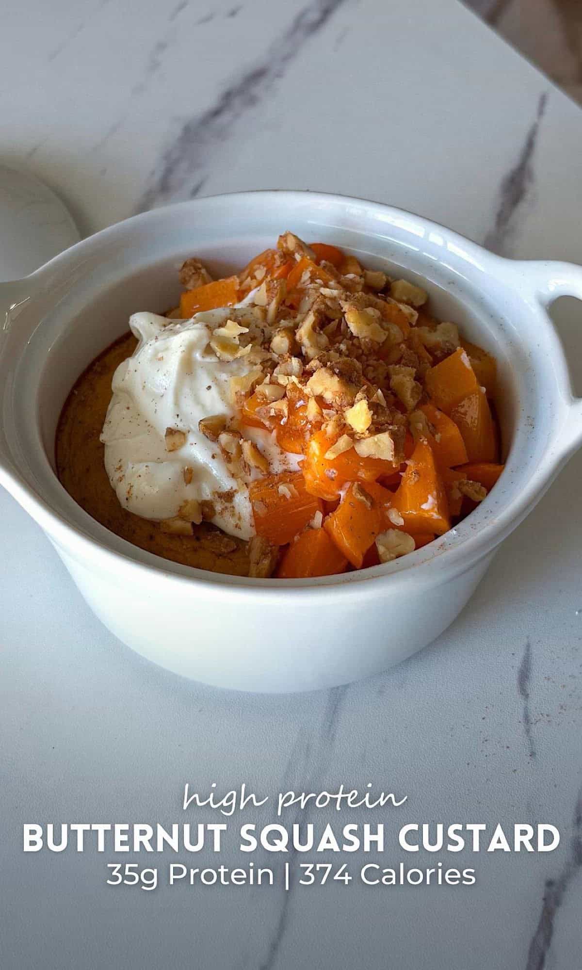 Butternut squash custard baked in a white ceramic ramekin, topped with creamy protein yogurt, diced persimmon, chopped walnuts, and a sprinkle of warm spices.