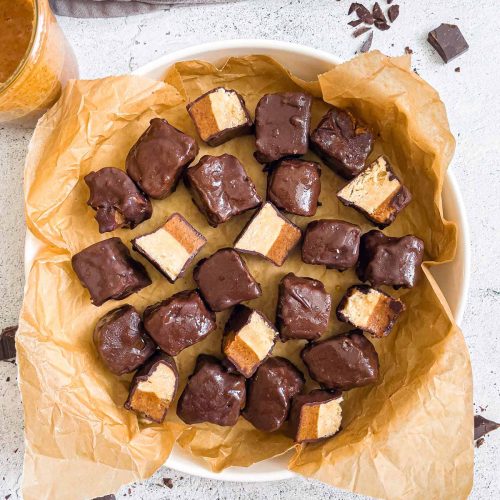 raw gluten free and vegan twix bites in large plate with some cut showing layers